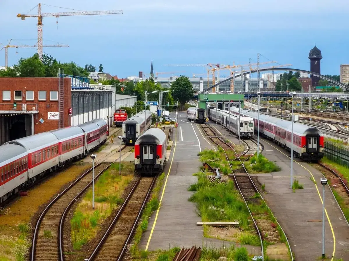 Pociągi na torach w Berlin Hauptbahnhof, z dźwigami budowlanymi w tle.