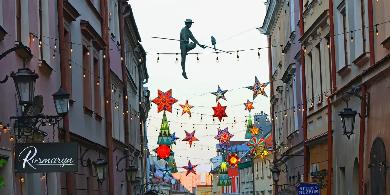 Lublin trasa: rzeźba akrobaty na linie, kolorowe gwiazdy i lampki nad ulicą Stare Miasto.