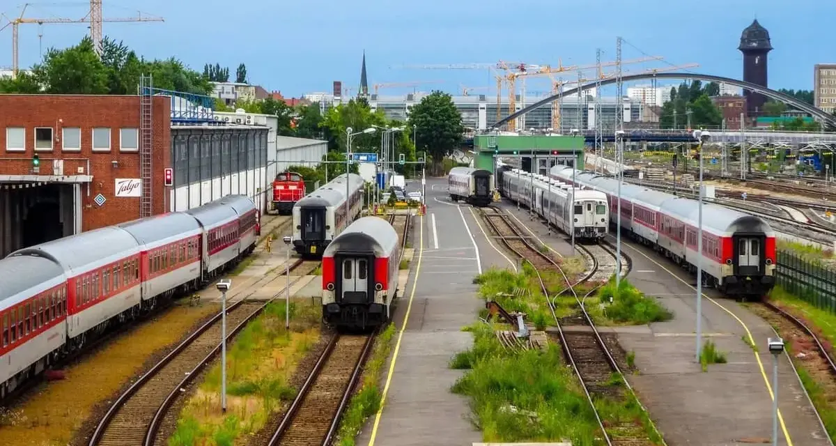 Pociągi na torach w Berlin Hauptbahnhof, z dźwigami budowlanymi w tle.