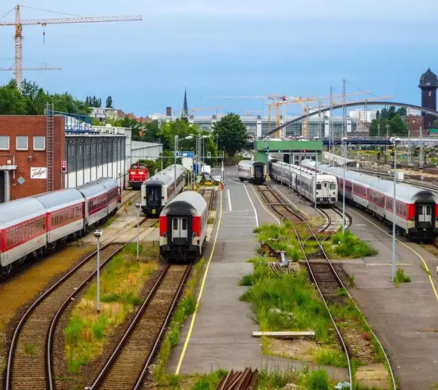 Pociągi na torach w Berlin Hauptbahnhof, z dźwigami budowlanymi w tle.