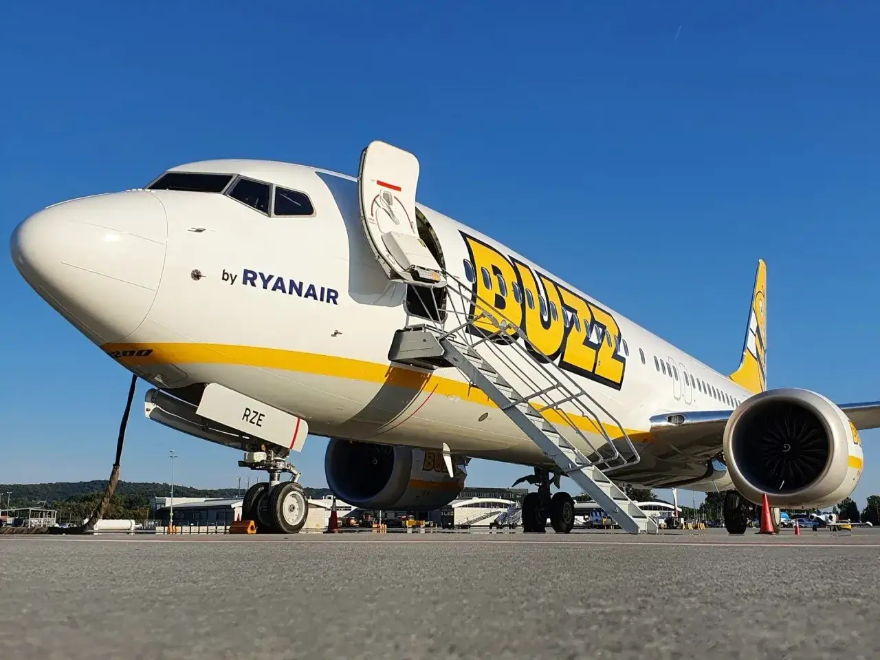 Samolot Ryanair z otwartymi schodkami, gotowy do lotu w promieniach słońca.