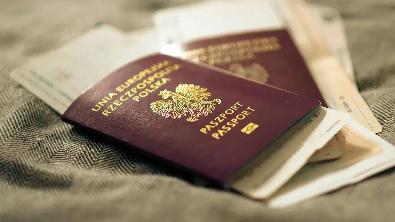 Polskie paszporty leżą na szarym materiale. Dowiedz się, jak wyrobić paszport, by podróżować po świecie.